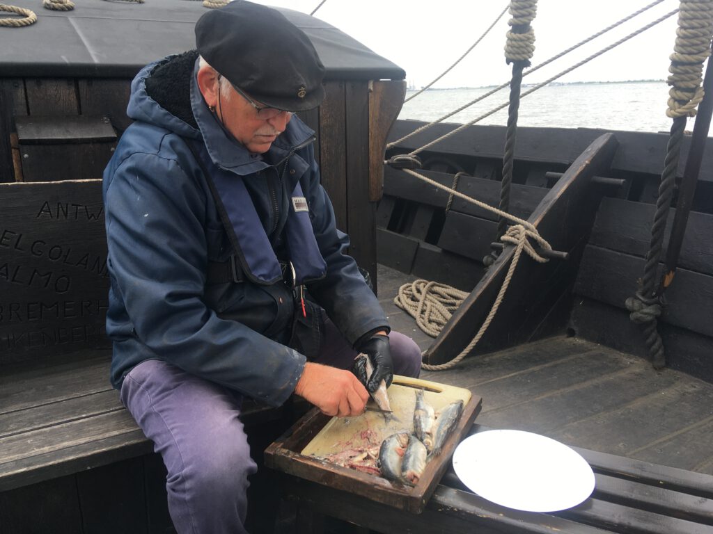 Haring schoonmaken op het dek van de Kamper Kogge